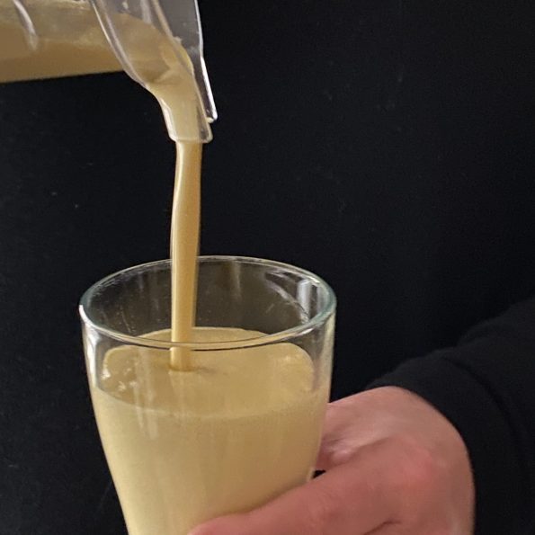 Mango lassi wordt ingeschonken in een glas vastgehouden door een hand