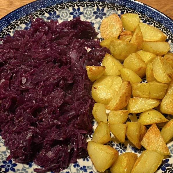 Bord met ovengebakken aardappeltjes en rodekool met appeltjes