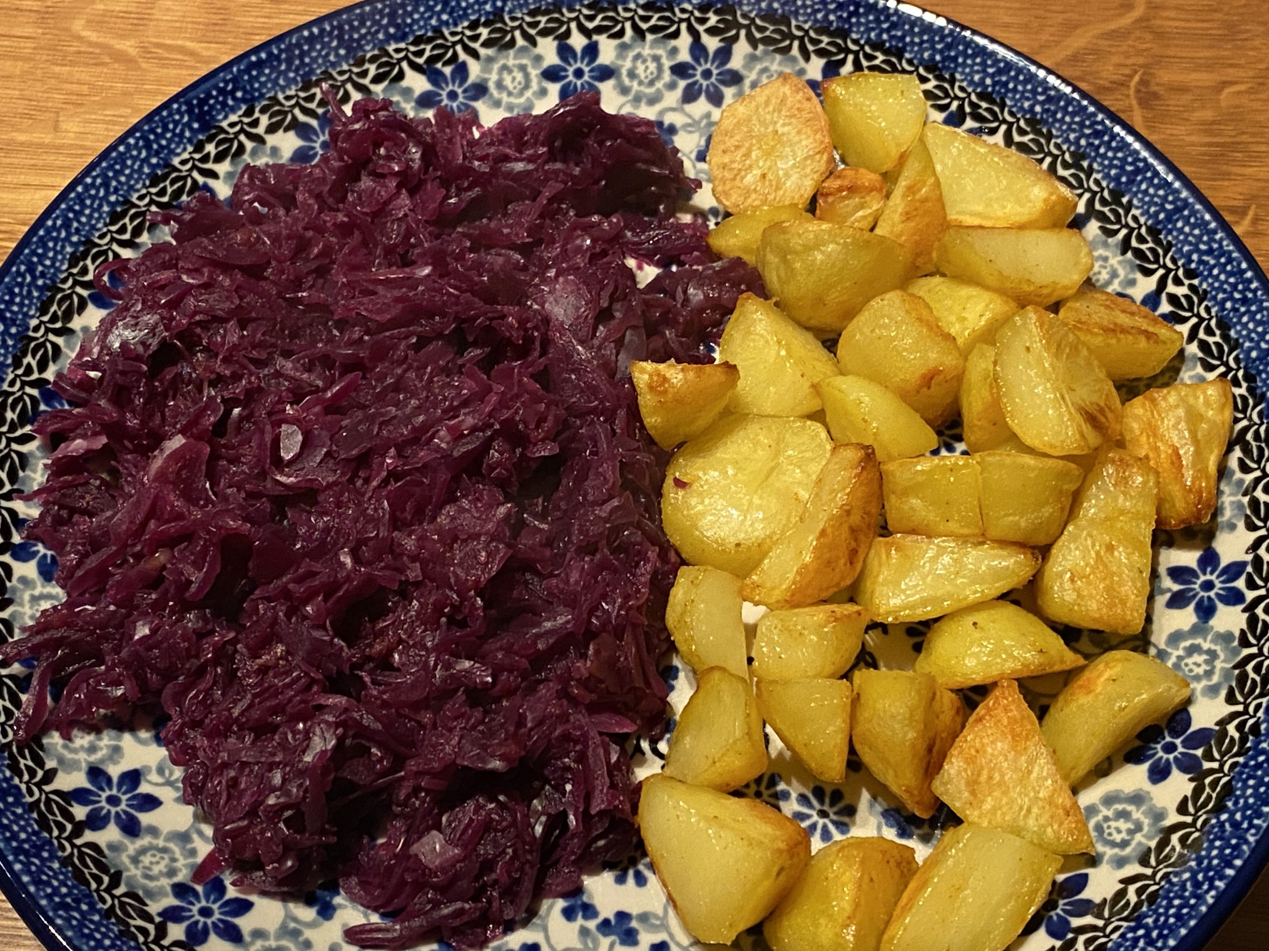 Bord met ovengebakken aardappeltjes en rodekool met appeltjes