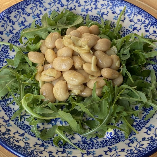 Limabonen in rozemarijn-knoflookboter op een bedje van rucola