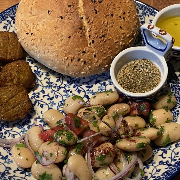 Bord met Turkse bonensalade, brood, falafel en sumak dressing