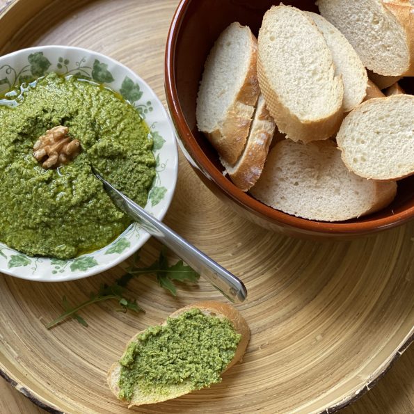 Een schaaltje rucola pesto met een walnoot en een schaal met stokbrood