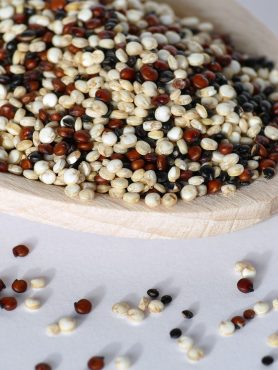 Lepel gevuld met ongekookte quinoa in drie kleuren