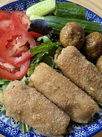 Bord met salade, aardappelkroketjes en vegan balletjes