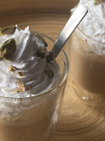 Twee glazen met pistache frappucino, slagroom en gehakte pistachenootjes