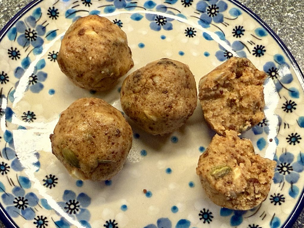 Een schotel met daarop 3 hele sattu ladoo’s en een doormidden gebroken ladoo.