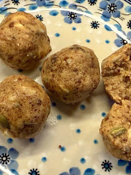 Een schotel met daarop 3 hele sattu ladoo’s en een doormidden gebroken ladoo.