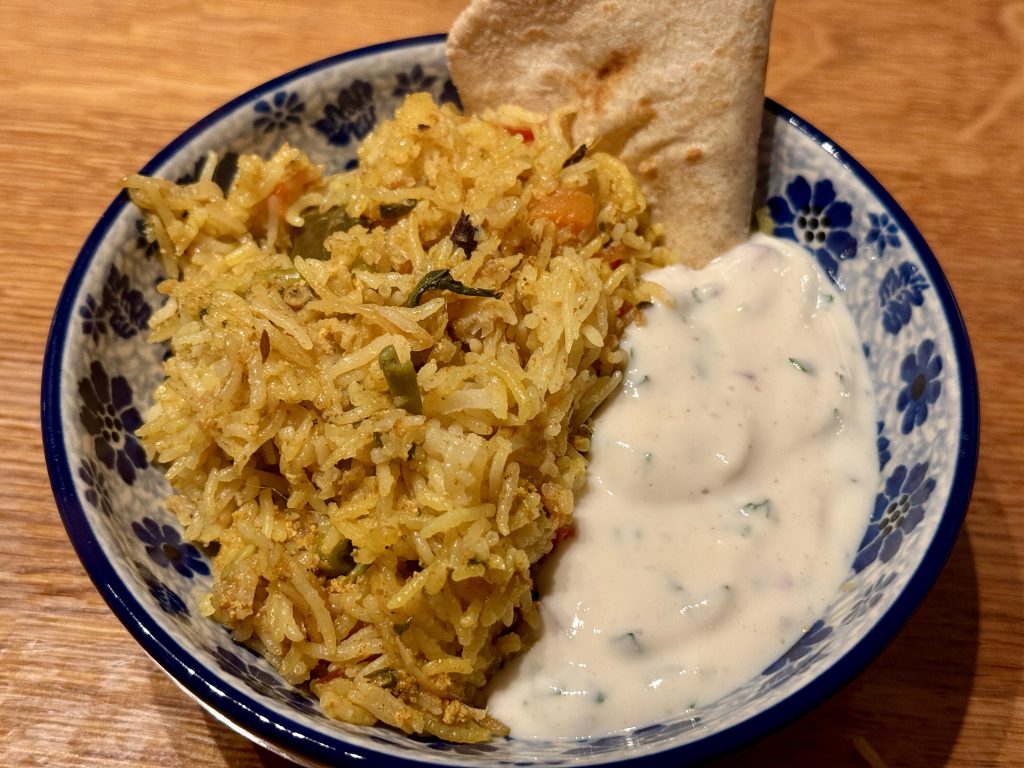 Een schaaltje met biryani, raita en roti